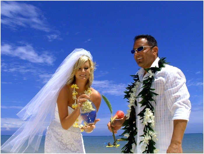 bride with long viel and groom with dark glasses pour sand together at ceremony